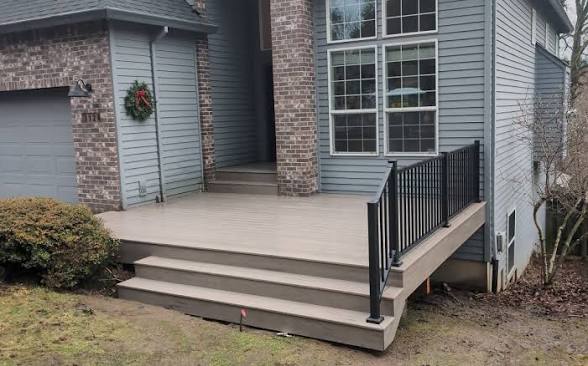 Front entry deck with light gray composite decking, wide steps and black aluminum railing