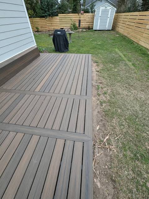 Two-tone composite deck with picture-frame border boards beside a fenced backyard