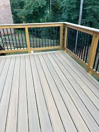 Freshly installed light gray composite deck boards with cedar posts and black balusters