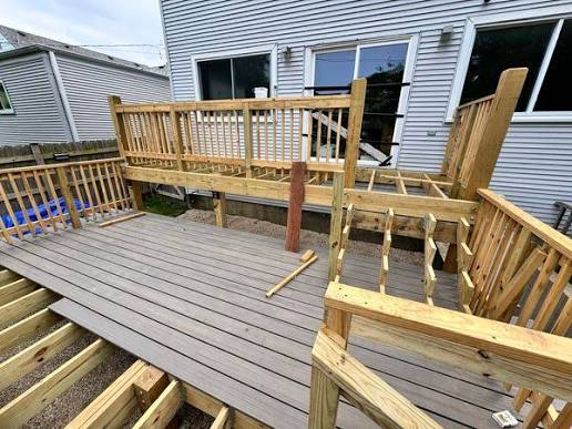 Deck rebuild in progress with new pressure-treated framing and railing posts