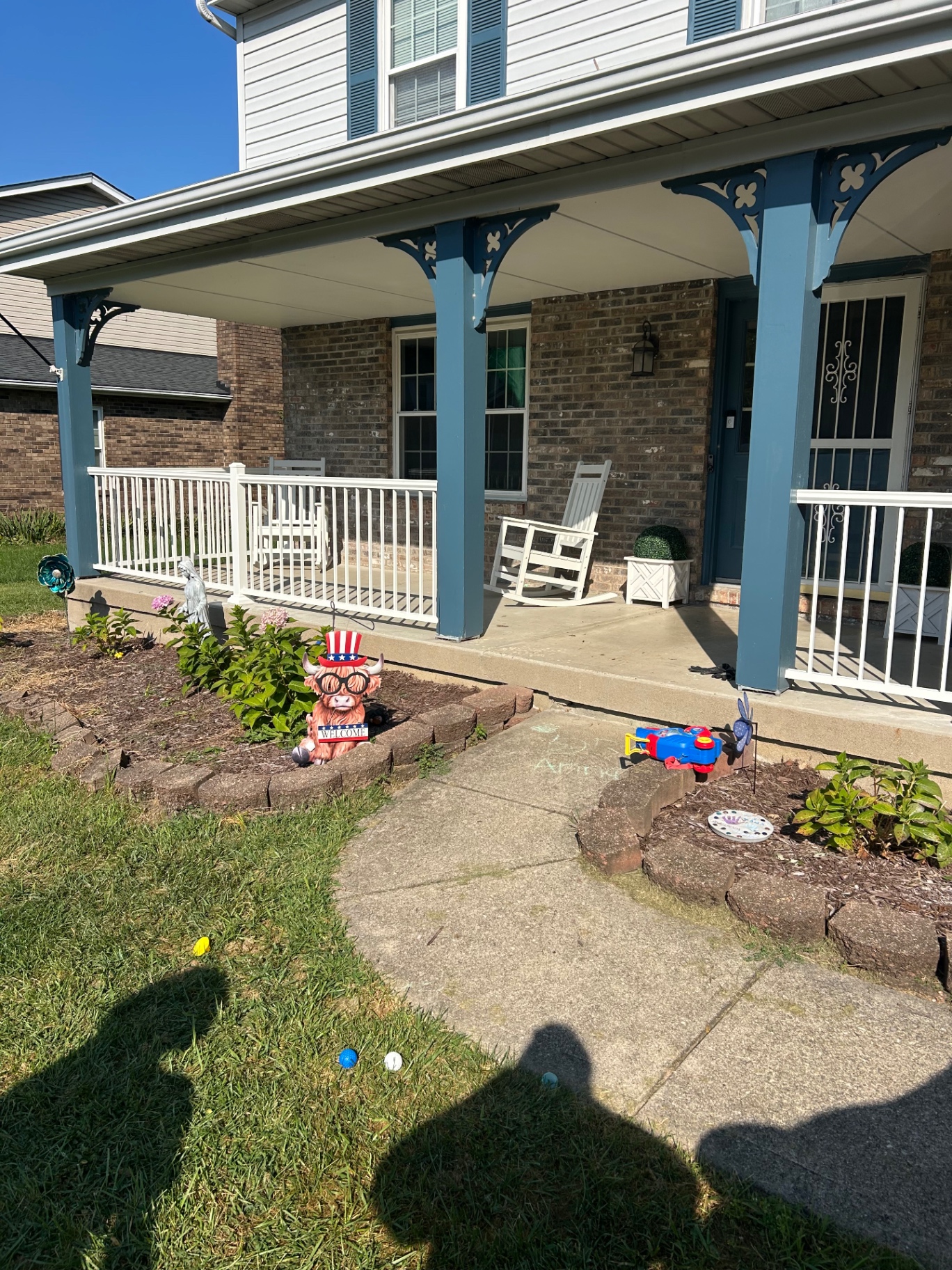 Covered brick front porch with new white vinyl railing and blue support columns