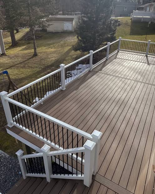 Elevated composite deck with white vinyl railing, black balusters and stairs to the yard