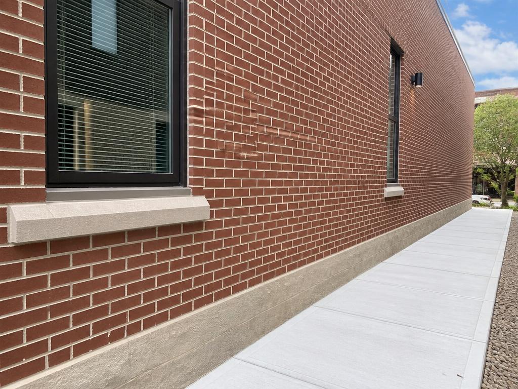 Restored brick wall with fresh tuckpointing and new concrete walkway