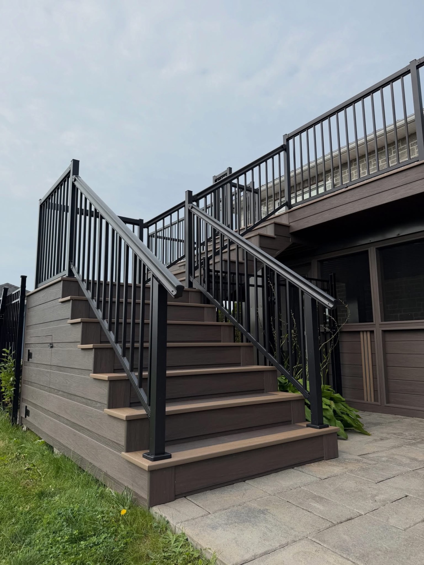 Composite deck stairs with black metal handrails leading up to a raised deck