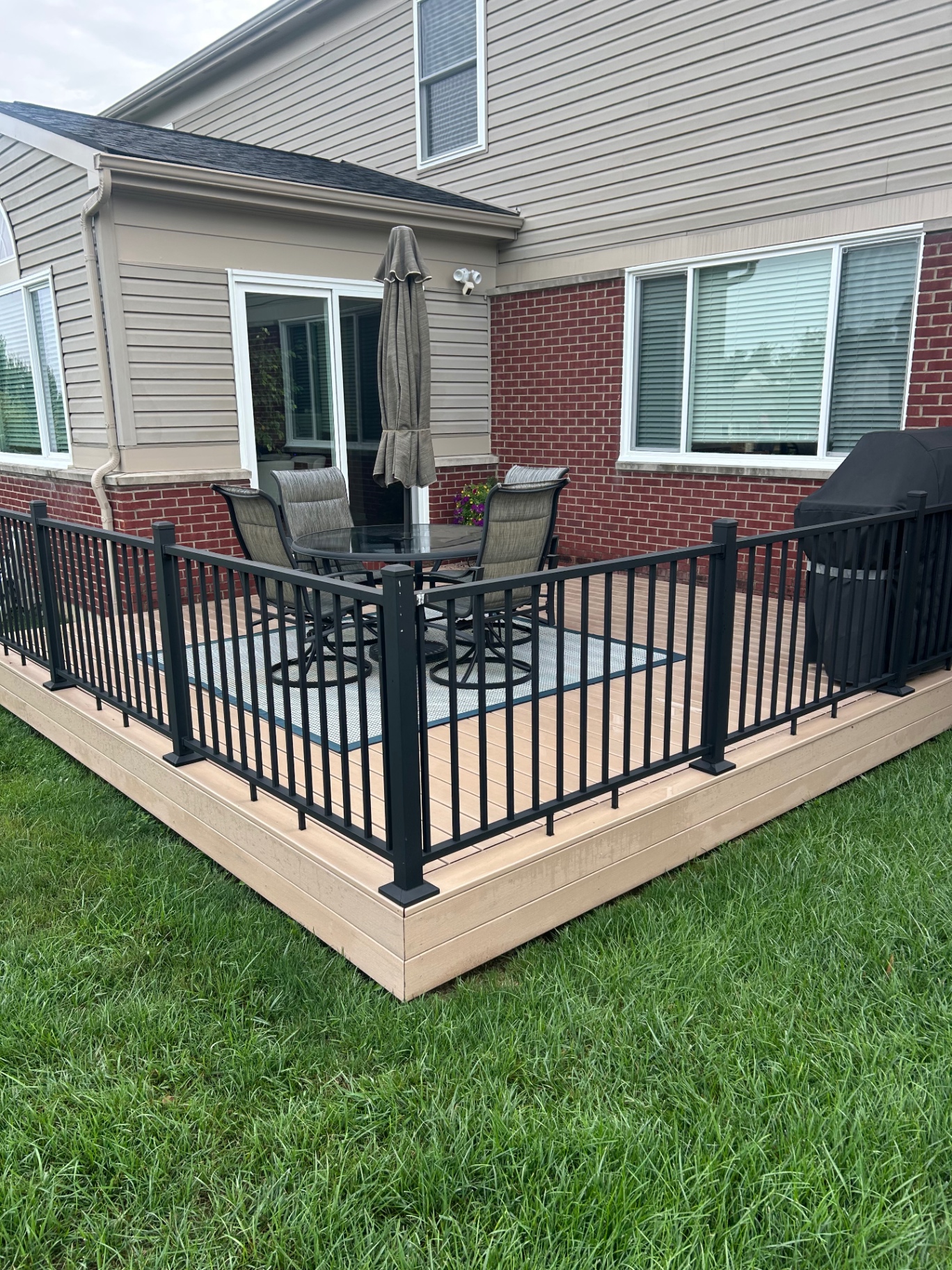 Ground-level composite deck with black aluminum railing and patio furniture