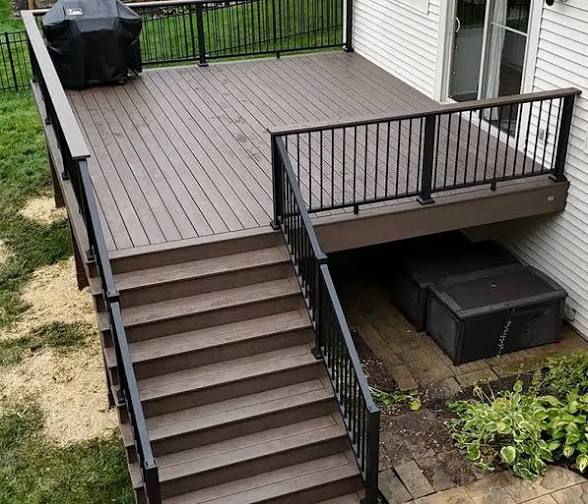 Completed brown composite deck with wide stairs and black aluminum railing system